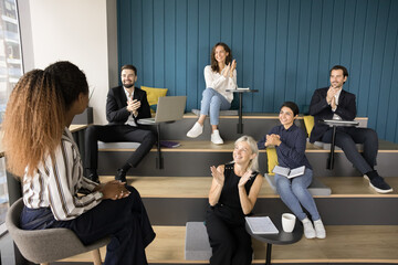 Diverse group applauding young African American presenter woman, clapping hands, thanking for presentation, lecture seminar. Female business teacher getting applause, recognition from audience