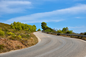 Naklejka premium Empty curvy asphalt road on the green mountain under the blue sky