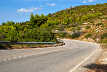 Empty curvy asphalt road on the green mountain under the blue sky