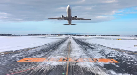 Foto auf Acrylglas Commercical white airplane fly up over take-off runway the (ice) snow-covered airport- Norway © muratart