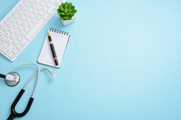 Stethoscope, computer keyboard, pen, note pad, and greenery on a blue background