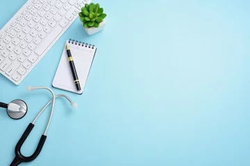 Foto op Plexiglas Stethoscope, computer keyboard, pen, note pad, and greenery on a blue background © 智 高