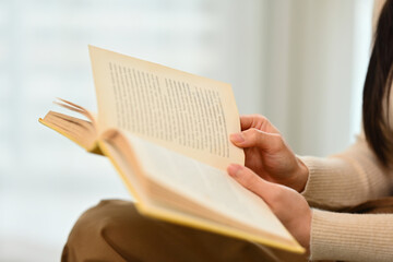 Young woman reading book, enjoying leisure weekend time at home. Education, leisure and lifestyle concept