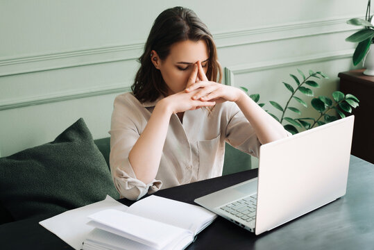 Fatigued Young Woman, Overworked and Dejected, Gazing at Computer Screen in Distress. Overwhelmed Young Woman Struggling at Computer Desk, Battling Overexertion and Weariness.