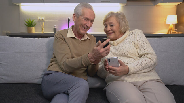 A happy old couple watching a funny video on a smartphone together, embracing modern technology