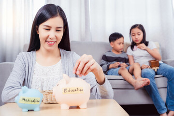 Obraz na płótnie Canvas Happy excited asian mother dropping coin into piggy bank Caring mom save money for the future for her kid She invest money collecting coins in piggy bank Family Education saving financial concept