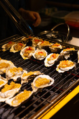 cooking charcoal grilled oysters with garlic sauce at vertical composition