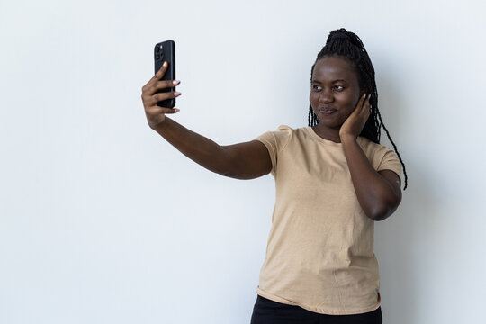 Attractive african woman with afro taking a picture of herself with her phone
