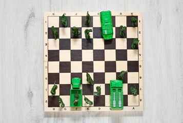 Concept of military aggression on the chessboard. Toy soldiers and military vehicles are fighting against each other. Top view.