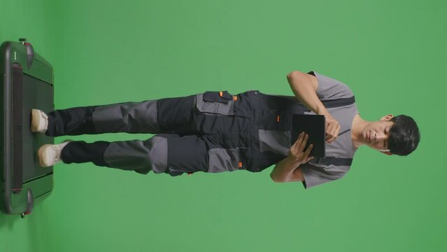 Full Body Of Asian Man Worker Taking Note On A Tablet While Walking In The Green Screen Background Studio
