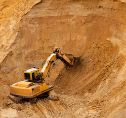 excavator extracts and loads sand into large truck in sand quarry