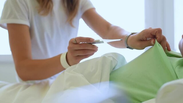A caring young mother takes her little son's temperature.