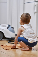 Naklejka premium little baby girl with a rag washing the tiled floor