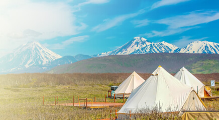 White glamping tents against the backdrop of volcanoes on the Kamchatka Peninsula