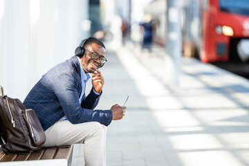 Portrait of happy businessman commuter waiting for the train at the station. Commuting to work. - obrazy, fototapety, plakaty