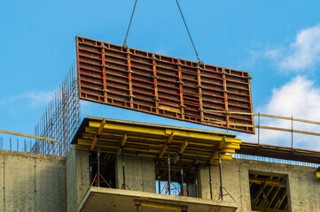 The crane lifts the formwork during the construction of a high-rise building made of monolithic concrete