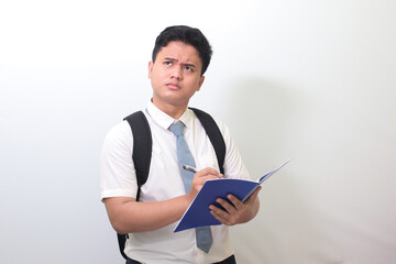 Indonesian senior high school student wearing white shirt uniform with gray tie writing on note...