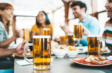 Happy people drinking beer at brewery pub restaurant - Group of friends enjoying happy hour sitting at bar table - Brewery life style concept with guys and girls dining together