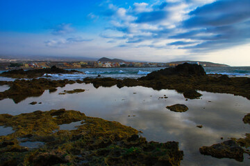 Tranquil Dawn: El Médano's Golden Hour with Waves, Rocks, and Sand