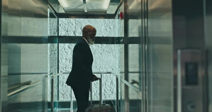 Elevator, travel and a mature black man at the office for business, corporate job or professional trip. Morning, arrival and an African manager with luggage or a suitcase for working at an airport
