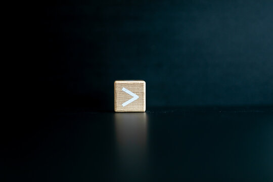 Wooden block written "greater than" with a Black background.