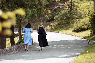 a pair of young girls. Back view of two attractive girls going in a public park. girlfriends or sisters are walking in the park, in the fresh air. Lifestyle. concept of love, family, walk