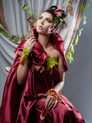 Glamorous portrait of a beautiful woman, Bright make-up. Autumn woman, decorated with autumn leaves