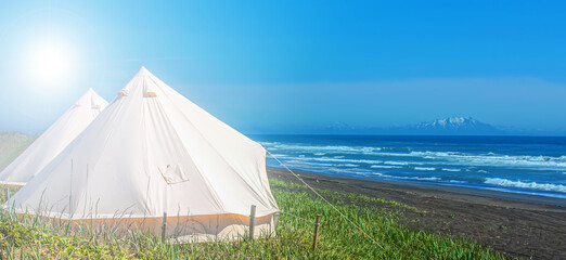 White glamping tents against the backdrop of the Pacific Ocean on the Kamchatka Peninsul
