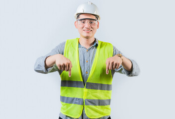 Smiling engineer pointing advertising down isolated. Smiling friendly engineer pointing down isolated