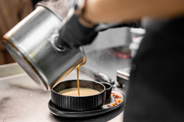 chef pouring mushroom cream soup in bowlon at the restaurant kitchen