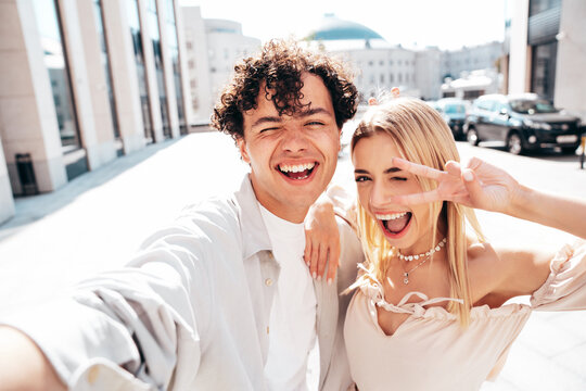 Portrait of young smiling beautiful woman and her handsome boyfriend in casual summer clothes. Happy cheerful family. Female having fun. Couple posing in the street background. Take Pov selfie photos