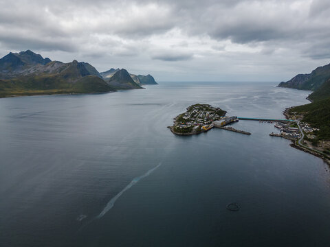 Aerial photo of Husoy fishing village island in Senja, Norway. Rocky mountains and cloudy sky.
