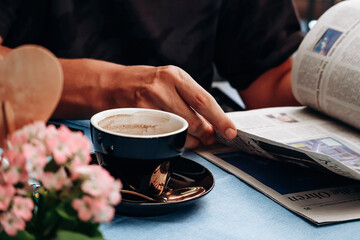 Obraz na płótnie Canvas Man reading a newspaper while drinking coffee in a restaurant
