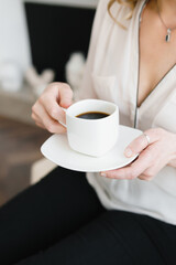 a cup of coffee in the hands of a woman in light clothes, homely atmosphere