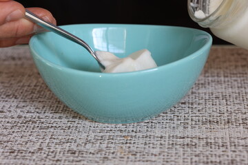 Teal colored bowl of yogurt with metal spoon