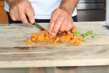 Chef prepping marinated carrots and sweet peas for cooking