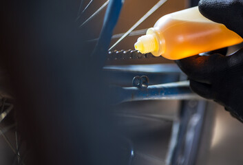 Man worker pouring oil on bicycle chain