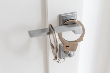 handcuffs on door handle in home background