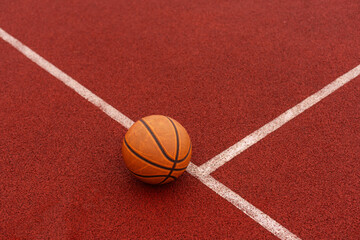 Orange basketball on brown court of gymnasium sport floor. Street basketball concept