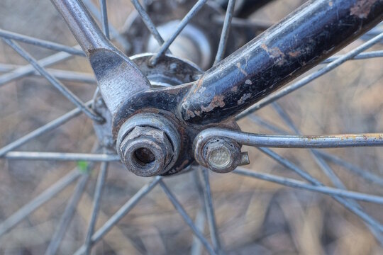 part of an old bicycle made of gray metal spoked wheels on a blue frame on the street