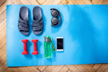 Fitness at home. Home slippers and fitness dumbbells. Blue fitness mat and equipment. Stay fit.