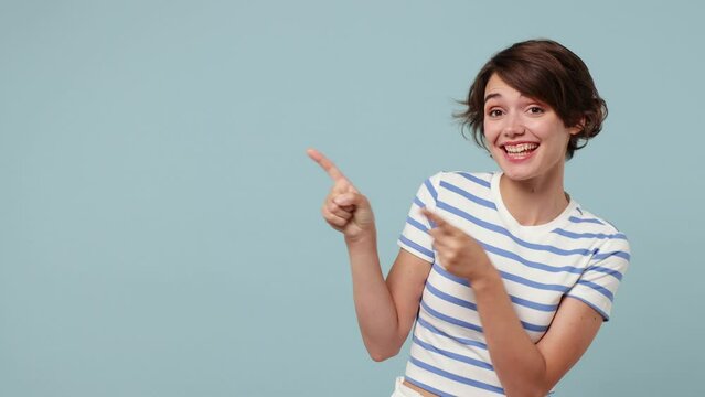 Young woman wear striped t-shirt casual clothes point index finger camera on you aside indicate index finger aside on workspace area copy space mock up isolated on pastel plain blue cyan background
