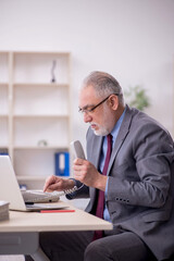 Old male employee working in the office