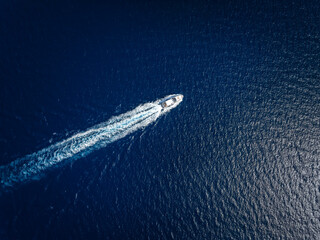 High aerial view of a luxury yacht traveling over the sparkling ocean - obrazy, fototapety, plakaty