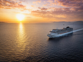Panoramic aerial view of a cruise ship traveling over the ocean during golden summer sunset time