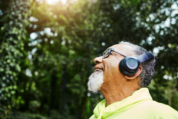 Headphones, nature and senior man hiking for health, wellness or cardio training on a mountain....