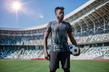 Intense portrait of a football player holding the ball in the stadium