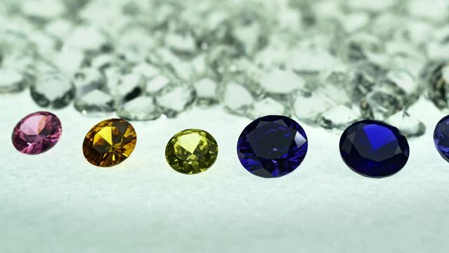 colorful gems are arranged in a row in front of a pile of white diamonds..light pendant shine on diamonds..beautiful colored diamonds surrounded by white diamonds..beautiful diamonds turning around