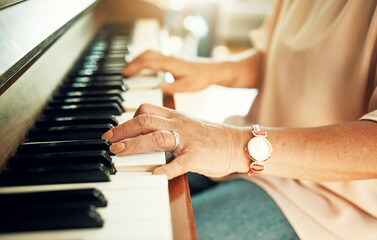 Hands, closeup and woman playing piano for music in living room for musical talent practice. Instrument, song and zoom of senior female person in retirement enjoying keyboard at modern home.