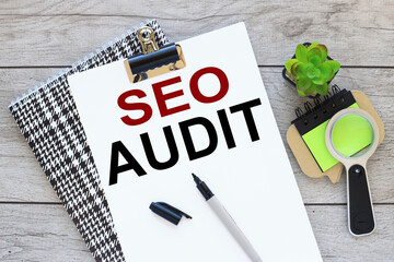 SEO AUDIT. Business concept. text on white A4 paper on a beautiful notepad. sticker magnifying glass